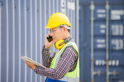 Foreman dock worker in hardhat and safety vest checking containers box from cargo, Engineer man with digital tablet checking and inspect the container