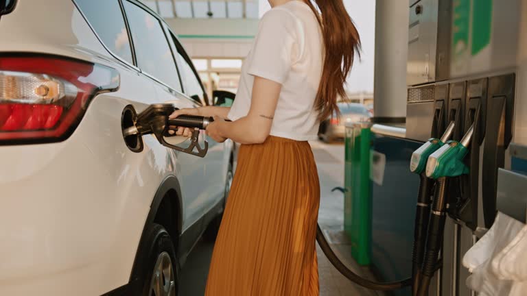 SLO MO Unrecognizable woman re-filling fuel in her car at the gas station