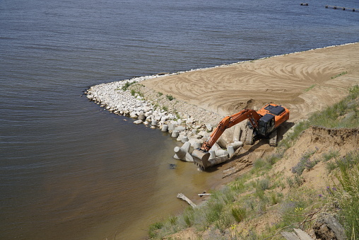 The excavator levels the sandy bank of the Volga River. Ulyanovsk. Russia.
