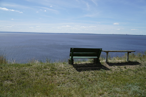 Old wooden benches on a high bank with a beautiful view of the Volga River. Ulyanovsk, Russia.