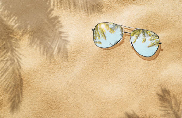 istock High angle view of sunglasses on the sand 1407634386