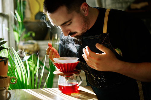 Professional barista preparing filter coffee using origami dripper. Alternative ways of brewing coffee