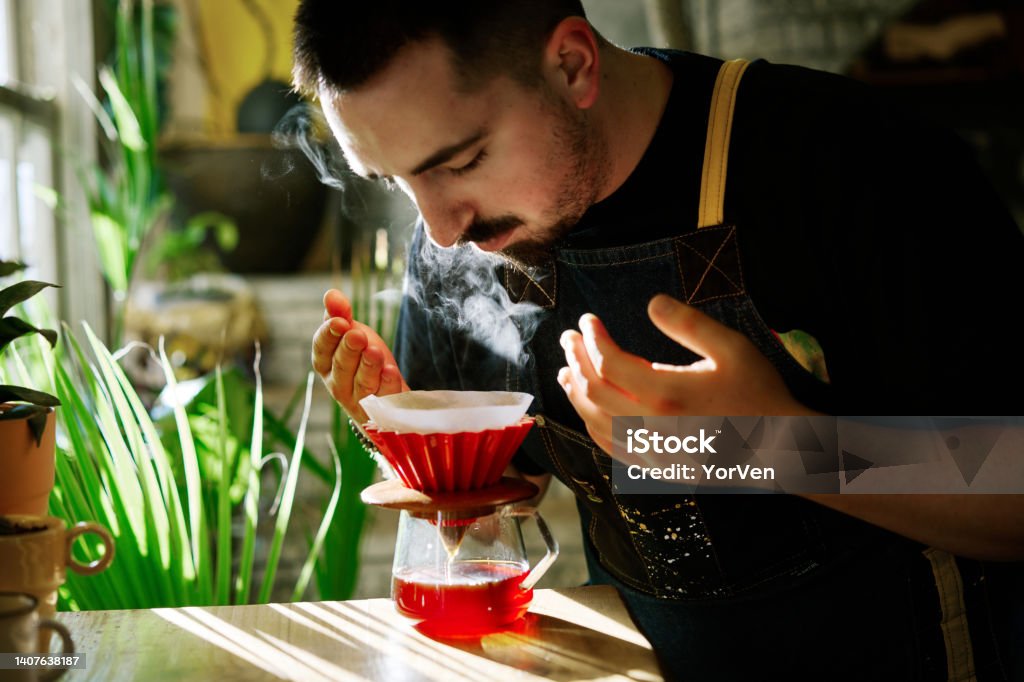 Barista smelling the filter coffee while making it Professional barista preparing filter coffee using origami dripper. Alternative ways of brewing coffee Scented Stock Photo