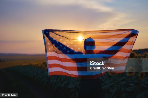 Rear View Of Patriotic Man Standing On The Sunflower Field With Usa Flag During Sunset National Holiday Concept Stock Photo - Download Image Now