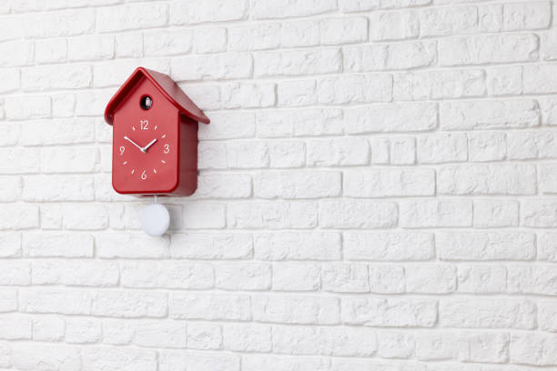 istock Cuckoo red clock with pendulum on a white brick wall 1407638594