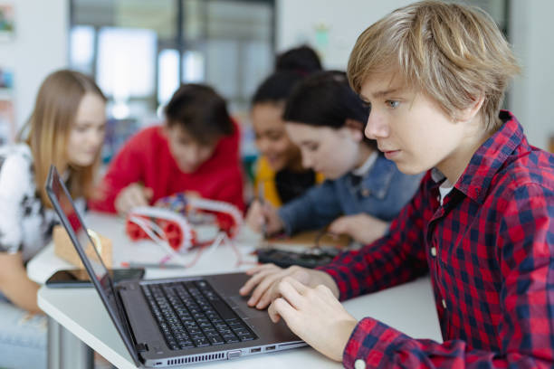istock Group of high school students building and programming electric toys and robots at robotics classroom 1407640538