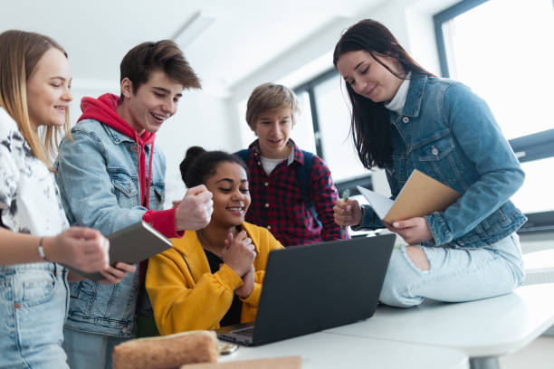 istock High school students sitting together at desk and using laptop and talking during break in classroom. 1407640782