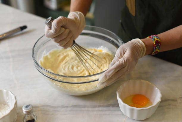 A hand in rubber glove stirring 
dough for a cake