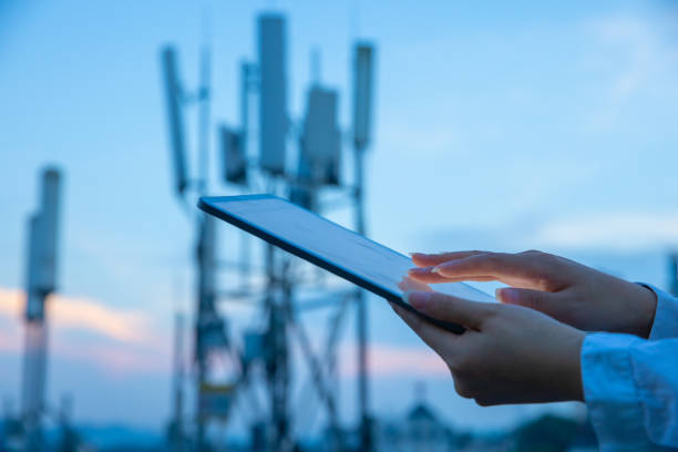 4g、5g通信塔の近くでデジタルタブレットを使用する人間の手 - tower communications tower mobile phone antenna ストックフォトと画像
