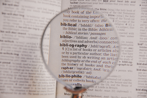 The definition of the word Bibliography in a dictionary, under magnifying glass, translator and language concept