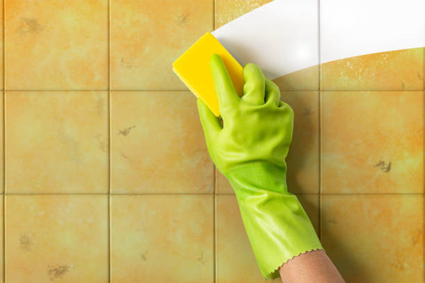 istock Dirty tile wall being cleaned by a hand with a sponge 1407651343
