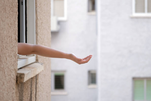 Open hand of a girl in a gesture of asking something leaning out of the window stock photo