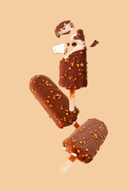 istock white popsicle in chocolate glaze with nuts flying on a beige background, selective focus 1407652264