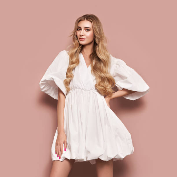 Blonde young woman in elegant white dress Blonde girl with perfect makeup. Smiling beautiful model woman with long curly hairstyle. Care and beauty hair products. Model in white festive dress dress stock pictures, royalty-free photos & images