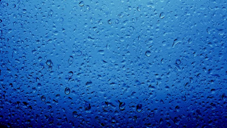 Background abstract of raindrops falling on a window glass with blue sky