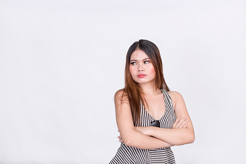 An uninterested woman with her arms crossed glanced at the subject of her annoyance. Wearing a striped sleeveless blouse. Isolated on a white background.