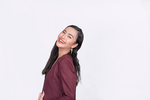 A Filipina woman showing her great personality. Side view and looking towards the camera smiling. Isolated on white background.