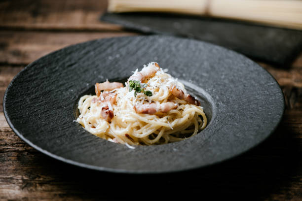 istock Spaghetti carbonara on a black plate 1407659360