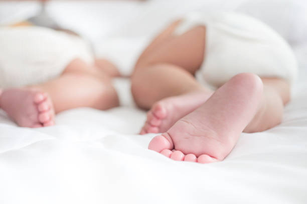 primi piani dei neonati sul letto, i bambini gemelli giacciono su una coperta bianca morbida, concetto di infanzia felice - twin newborn baby baby girls foto e immagini stock
