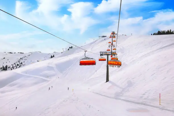 Chair ski lift with orange bubble shelter and ski slope in Saalbach resort, Austria, Alps, Europe.