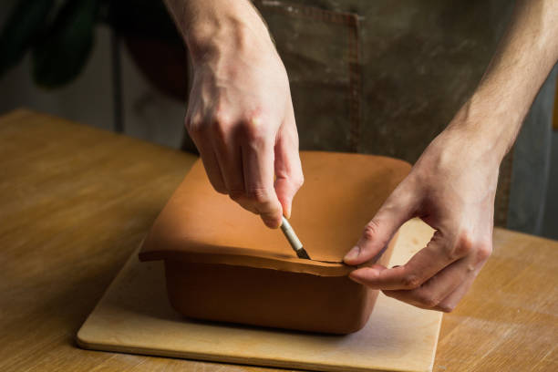istock Potter cuting clay. Master working in Pottery studio with raw ceramic roasting dish. Art hobby 1407668544
