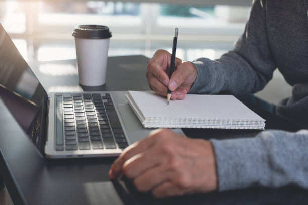 istock Online learning digital education concept, Man hand writing on notebook, surfing the internet on laptop computer working from home 1407669405