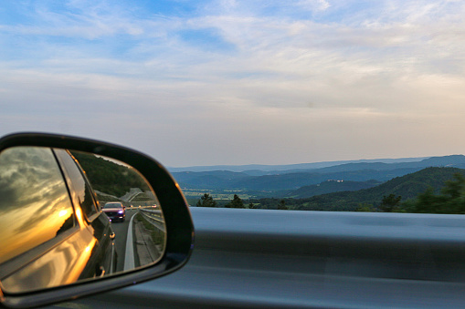 Road from Rovinj to Rijeka in croatia lies through a beautiful landscapes of mountains, rivers and beaches. Reflection in a car mirror shows a beautiful sunset.