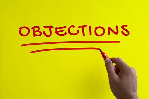 Hand writing objections text on yellow background. Objections concept