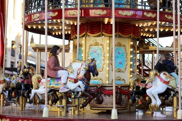 Photo of a little girl riding on animals on roundabout carousel in amusement park. child having fun on family weekend or vacations