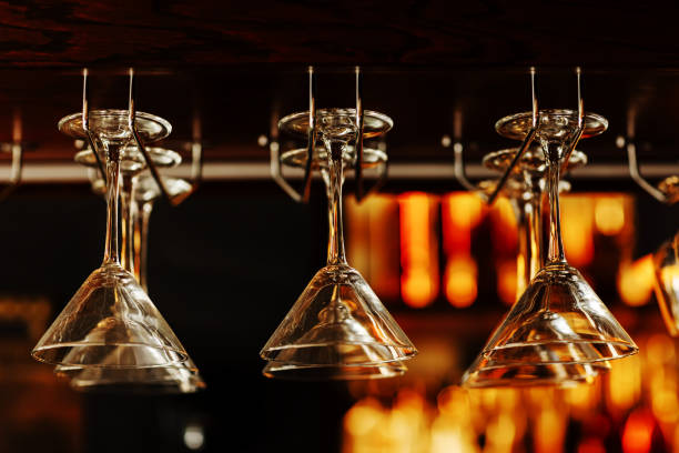 istock Empty clean upside-down crystal martini glasses hanging from the bar in luxury restaurant. Selective focus blurred colourful background. 1407676891