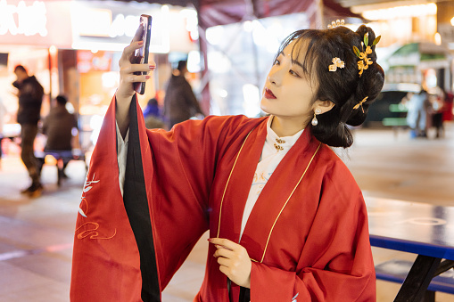 At night, a Chinese woman in Han costume took a selfie in the pedestrian street