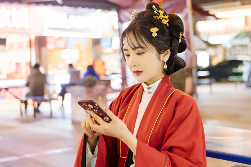 At night, a Chinese woman in Han costume used her mobile phone