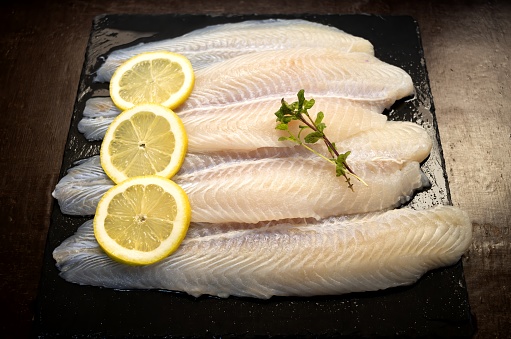 Panga fillets, Pterogymnus laniarius white fish from Asia, mild flavor with lemon slices and dark background
