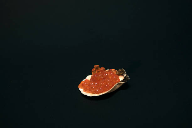istock Oyster shell with red caviar on a black background. 1407684622