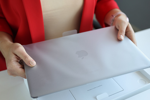 Minsk, Belarus - April 7, 2022: Woman holds an Apple Macbook Pro laptop in package concept