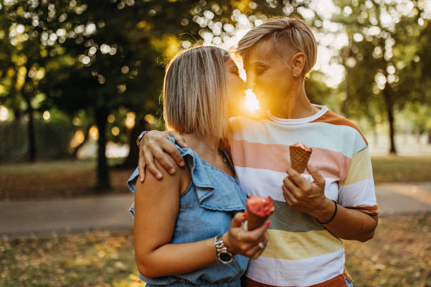 deux femmes amoureuses dans le parc mangent de la crème glacée - lesbian homosexual kissing homosexual couple photos et images de collection