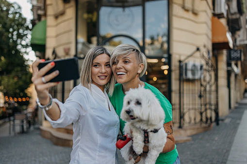 Beautiful happy lesbian couple making selfie on smartphone.