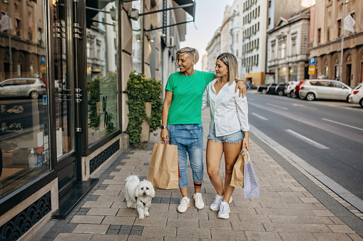 Happy female couple shopping together with their dog