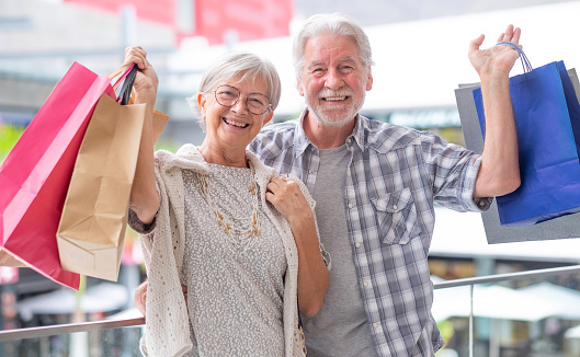Cheerful caucasian senior couple carrying shopping bags enjoying shopping, consumerism sales customer shopping concept