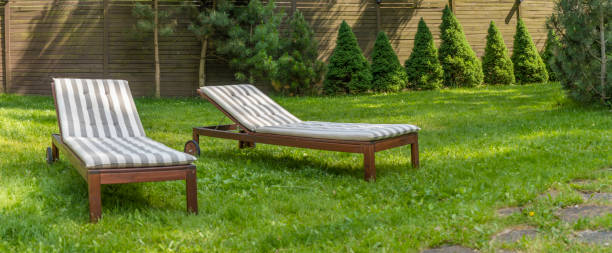 istock Lounge chairs on the backyard in a beautiful garden. Two empty sunbeds on the grass. 1407699311