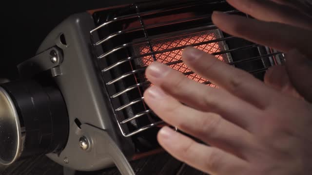 Portable gas ceramic heater for camping, warming my hands, close-up.