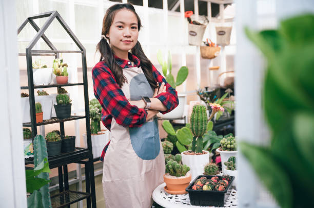 Beautiful Asia owner small business woman holding cactus in small shop cactus Beautiful Asia owner small business woman holding cactus in small shop cactus greenhouse nightclub nyc photos stock pictures, royalty-free photos & images