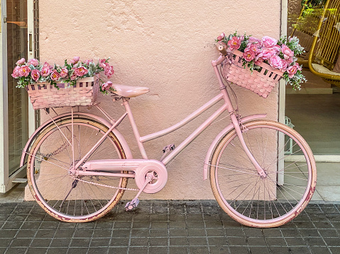 Valencia, Spain - June 28, 2022: View of bicycle painted in pink color lying on the wall. Beauty salons for women usually use this kind of decorations to attract customers to their shops