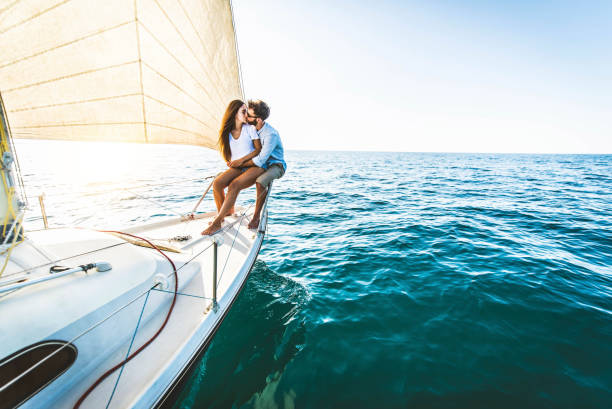 Young couple relaxing on yacht cruise - Two lovers enjoying summer vacation experience on sail boat at the sea - Summertime holidays and luxury travel concept Young couple relaxing on yacht cruise - Two lovers enjoying summer vacation experience on sail boat at the sea - Summertime holidays and luxury travel concept sailing couple stock pictures, royalty-free photos & images