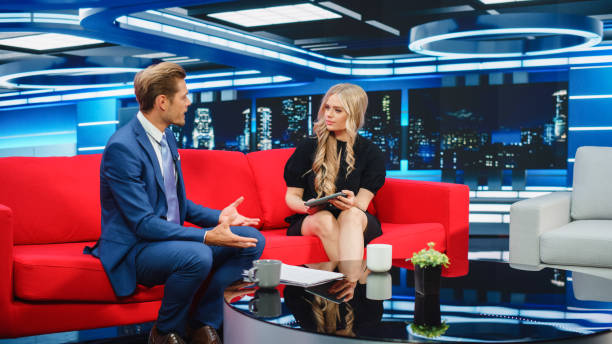 istock Talk Show TV Program: Two Charismatic Presenters Talk. Cable Channel Hosts Have Conversation, Chat, Discuss News, Interview Guests, Have Fun. Mockup of Television Studio. Wide Shot 1407703081