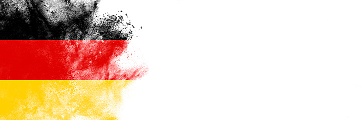 Abstract exploding powder in colors of German flag, isolated on white background with lot of copy space.