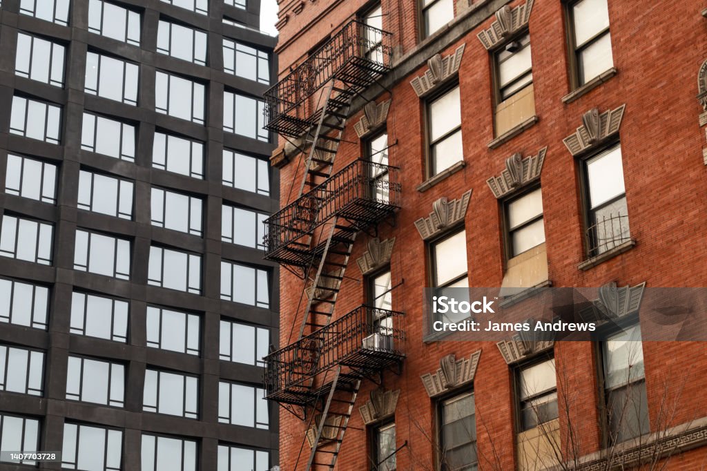 Old Brick Building with Fire Escapes next to a Modern Residential Skyscraper in Tribeca of New York City Looking up at an old brick building with fire escapes next to a modern residential skyscraper in Tribeca of New York City New York City Stock Photo