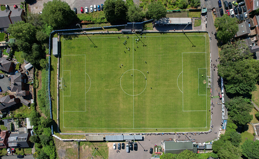 Aerial drone top view of football soccer field with people playing, housing estate UK, Skuna Stadium, Atherton Collieries