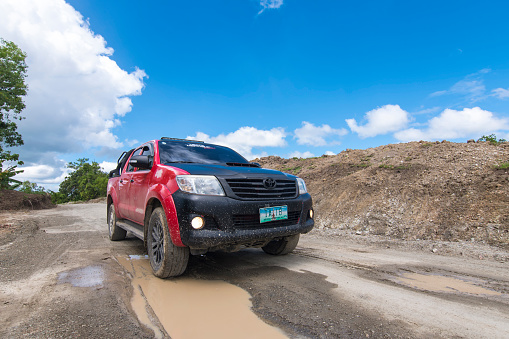 Buenavista, Bohol, Philippines - Nov 2021: A Toyota Hilux traverses an unpaved and muddy dirt road in the interior of Bohol. Off road adventure and exploration.