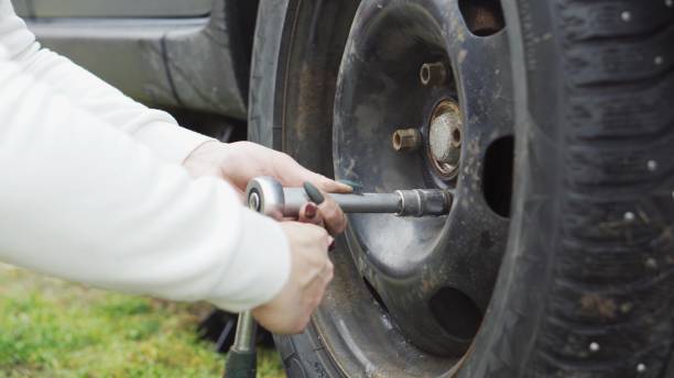 istock A girl with a manicure changes a car wheel, jack, wrench, grease. 1407709731
